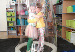 Widok na dwie dziewczynki zamknięte w bańce mydlanej.